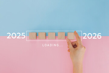 Hand assemble wooden block cube to update technology downloading tool bar status from 2025 to 2026, Merry Christmas and happy new year concept
