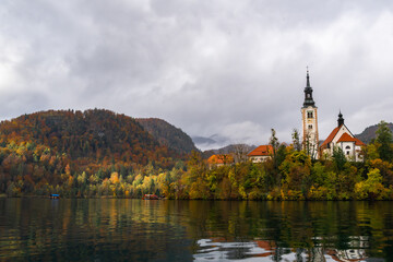 Scenic autumn view of Lake Bled featuring the church on the island and vibrant fall forest in Slovenia