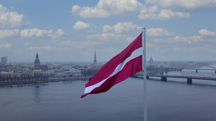 Drone View Of Riga Old Town With Latvian Flag Waving In Foreground Aerial Panorama Of Historic City Center, Daugava River And Urban Skyline On A Outumn Day In Latvia