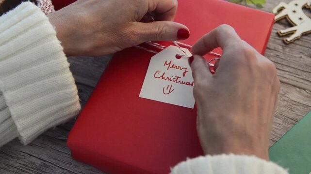 A woman preparing a Christmas present wrapped with red paper. 