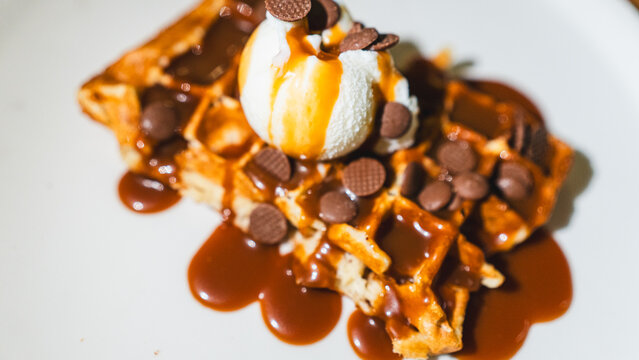 Crispy waffle topped with vanilla ice cream, chocolate sauce, caramel, and fresh fruits. A decadent dessert ready to eat, perfect for indulgent treats and cafes.