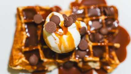 Crispy waffle topped with vanilla ice cream, chocolate sauce, caramel, and fresh fruits. A decadent dessert ready to eat, perfect for indulgent treats and cafes.