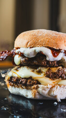 Delicious juicy burger with melted cheese, crispy bacon, mayo, and homemade barbecue sauce on a beautiful plate. Perfect comfort food for gourmet meals and promotions.