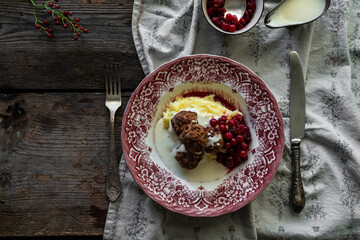 Traditional Swedish meatballs with mashed potatoes, cranberries and creamy gravy in vintage plate on wooden table. Homemade dinner. Comfort food.