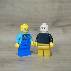 Naklejka premium Two Lego minifigures standing together on a wooden surface