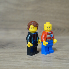 Naklejka premium Two Lego minifigures standing together on a wooden surface