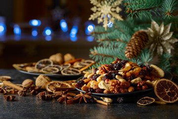 Christmas spices, various nuts, raisins, and dry citrus slices on a kitchen table.