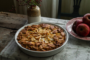 Homemade apple pie decorated with crust on wooden table in rustic kitchen.