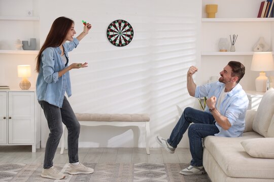 Man and woman playing darts at home