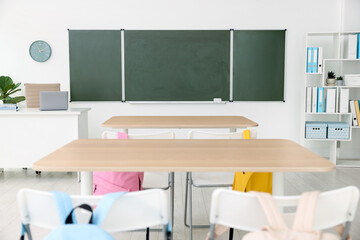 Green chalkboard, desks and chairs in classroom. Mockup for design