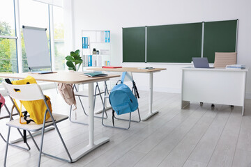 Green chalkboard and stylish furniture in classroom. Mockup for design
