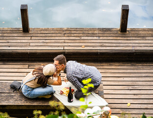 Young couple sharing a romantic engagement moment by Lake Bled wooden dock in autumn