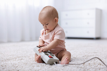 Cute little baby with power strip on floor at home