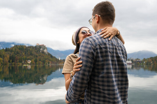 Young couple embracing during a romantic marriage proposal by lake Bled with autumn foliage in Slovenia - Powered by Adobe