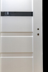 Installation of a black door handle with a lock for a white wooden door,