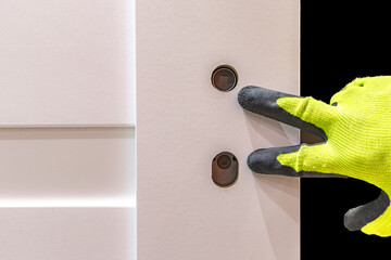 Installation of a black door handle with a lock for a white wooden door,