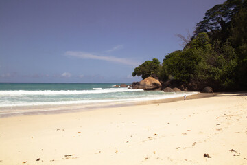 Solitary child walking on tropical beach with turquoise waves, Mahé, Seychelles