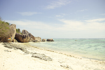 La Digue Island beach with iconic granite rocks, turquoise Indian Ocean waters, and soft white sand under a sunny blue sky, Seychelles paradise scene.
