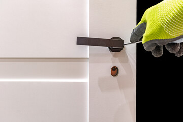 Installation of a black door handle with a lock for a white wooden door,