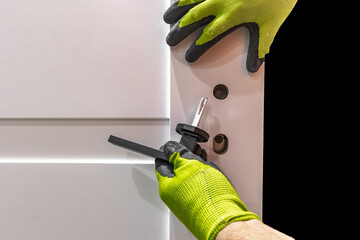 Installation of a black door handle with a lock for a white wooden door,