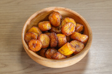 Aloco, accompagnement de bananes frites dans un bol sur une table en bois