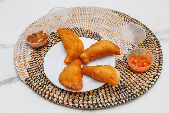 Pastels faits maison (viande ou thon) dans une assiette blanche, accompagn&eacute;s de sauces, entr&eacute;es africaines. Sp&eacute;cialit&eacute; s&eacute;n&eacute;galaise. 