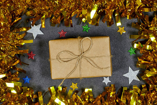 Wrapped Gift Box With Twine Bow Surrounded By Gold Tinsel And Star Confetti For Festive Celebration - Powered by Adobe