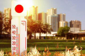 Thermometer showing high temperature against city during hot day
