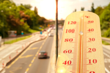 Thermometer showing high temperature against road in city during hot day