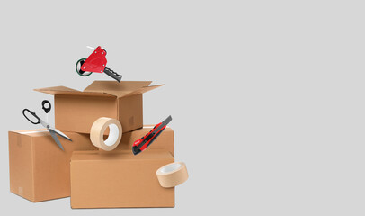 Cardboard boxes, scissors, paper knife, dispenser and adhesive tape in air on light grey...