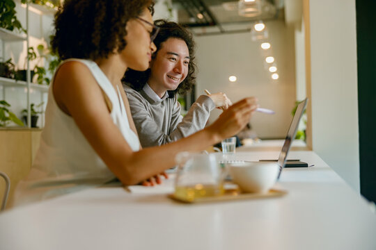 collaborative colleagues analyzing data on phone screen over coffee and laptops with smiles