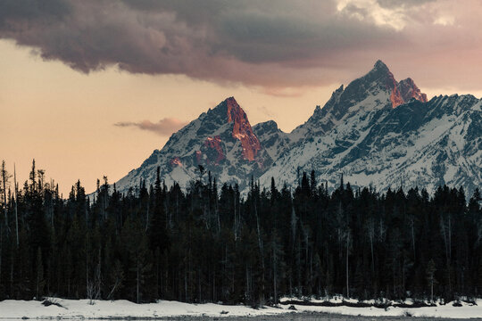 Snowy mountain glowing in a warm sunset at Grand Teton National Park. - Powered by Adobe