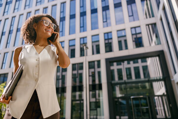 ambitious businesswoman exuding confidence while adjusting her glasses in bustling urban landscape