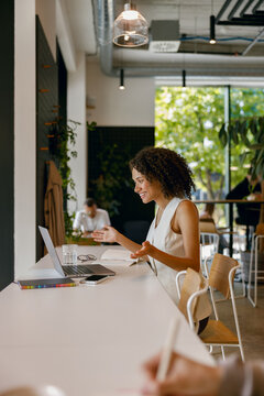 undistracted woman engrossed in work on her laptop in peaceful cafe environment with greenery