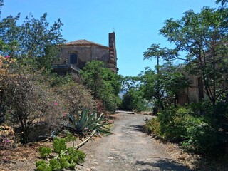 Una strada sterrata con veduta laterale dell'antica chiesa del borgo abbandonato di Carcaci.