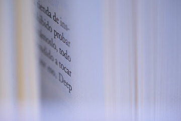 Shallow depth of field macro of book pages from the side with Spanish text partially visible. Minimalist image for literature, storytelling and language concepts.