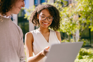 two female colleagues exchanging strategies and reviewing presentations in bright outdoor