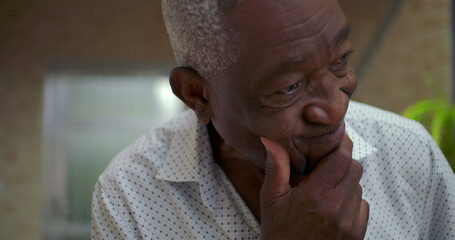 Elderly African American man resting chin on hand, showing concern with a pensive and introspective demeanor, reflecting deeply on life choices in a thoughtful moment indoors