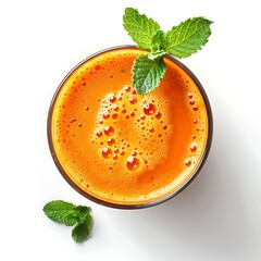 Overhead view of orange juice in a glass with mint leaves on a white background