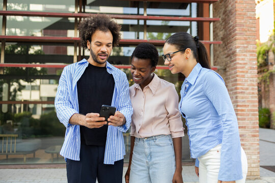 Business team reviewing project on smartphone outside