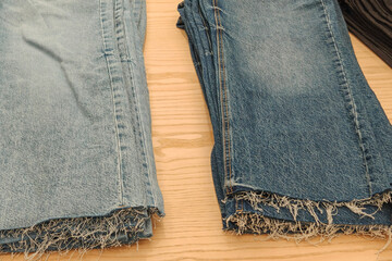 Denim jeans with frayed hems displayed on a wooden surface in fast fashion store