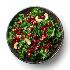Overhead view of a bowl filled with salad containing kale pomegranates and cashew nuts