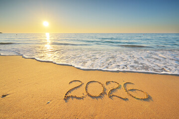 2026 text symbol of new year on the sea sand beach shore during sunset.