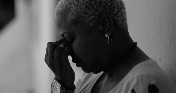 African American woman bowing her head, covering her face in a gesture of despair and vulnerability, reflecting emotions like regret, remorse, depression, and mental illness - Powered by Adobe