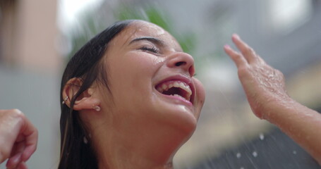 Young girl laughing joyfully under an outdoor shower during a summer day, radiating happiness and carefree energy in a refreshing and playful moment outdoors