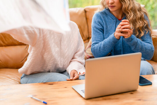 Friends discussing ideas while working on a laptop at home during a cozy afternoon together