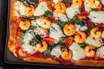 Pizza with shrimp, tomatoes and spinach, close-up. Mediterranean pizza texture background