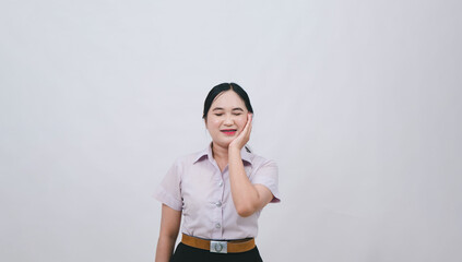 Young woman braces in a light purple shirt and black skirt smiling confidently while touching her cheek against a plain white background, showcasing natural beauty and positivity