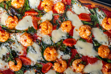 Pizza with shrimp, tomatoes and spinach, close-up. Mediterranean pizza texture background