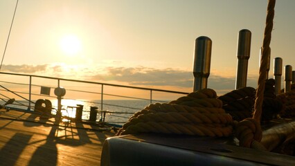 sunset at sea through the rigging of a sailboat
